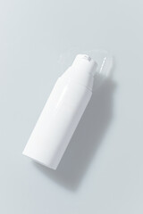 White cylindrical bottle mock up with a pump top, on a light gray surface
