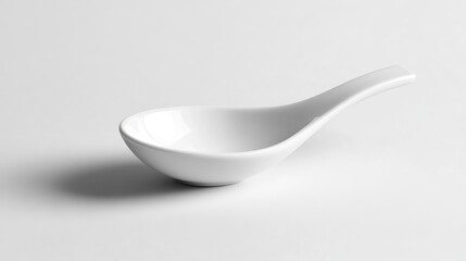 Elegant white ceramic spoon with a sleek design resting on a smooth, minimalistic white background, showcasing its refined shape and glossy finish.