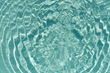 Blue water with ripples on the surface. Defocus blurred transparent blue colored clear calm water surface texture with splashes and bubbles. Water waves with shining pattern texture background.