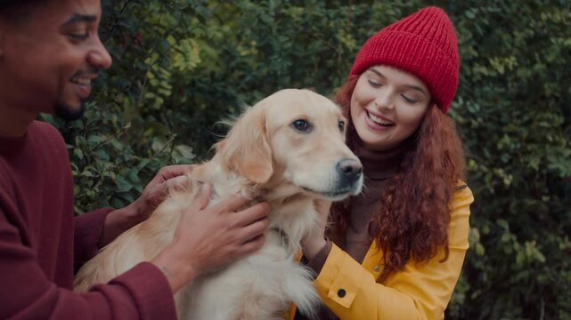 Multiracial friends couple pets golden retriever with smile