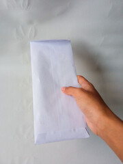 Asian female hand giving white envelope isolated on white background
