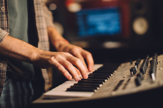 Close-up. A musician plays the keyboard in a recording studio.