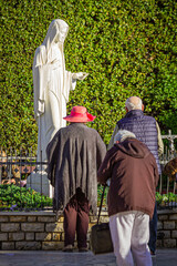 Statue of the Virgin Mary in Medjugorje with Pilgrims in Prayer | Figurka Matki Boskiej w Medziugorje z modlącymi się pielgrzymami | Gospina figurica u Međugorju s molećim hodočasnicima