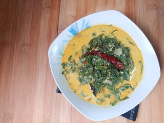 Indonesian traditional food 'Gulai Daun Singkong' or made from Tapioca or cassava leaves cooked with coconut milk, selective focus