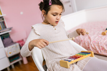 Girl with autism plays metallophone. Music therapy at home