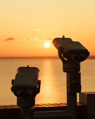 Binoculars on the terrace of Tihany Abbey. An amazing sunrise in the background, with the sun...