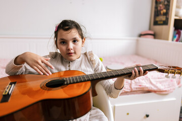 Little girl with autism plays guitar. Music therapy at home.