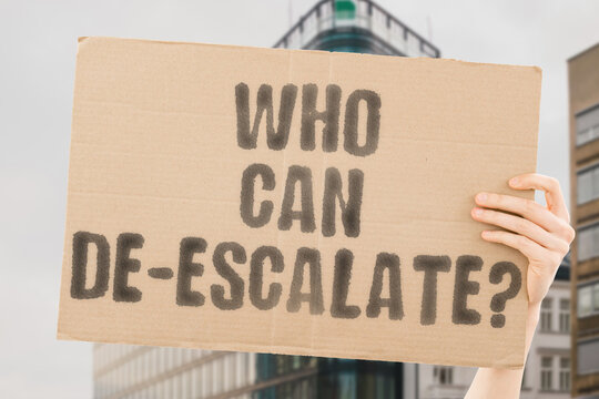 The phrase 'Who can de-escalate?' on a banner in a person's hand. Human holds a cardboard with an inscription. Peace. Resolution. Diplomacy. Leadership. Mediation. Stability. Unity