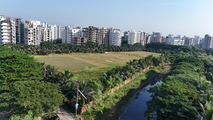A beautiful green field aerial drone view sky top-down isolated in the middle of city buildings is located in Dhaka Bangladesh