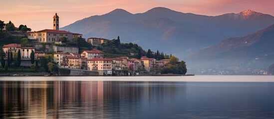 Naklejka premium Scenic view of Cannobio on Lago Maggiore with tranquil waters and mountains at sunset in a picturesque Italian setting