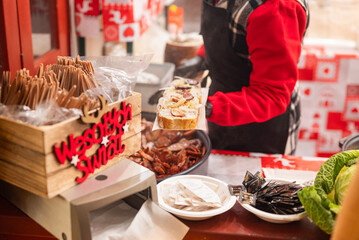 vendor fries meat and sausage and potato on the grill in the city center at the Christmas market in Gdansk Poland.with text 