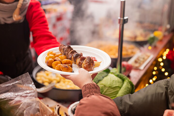 vendor fries meat and sausage and potato on the grill in the city center at the Christmas market in Gdansk Poland.