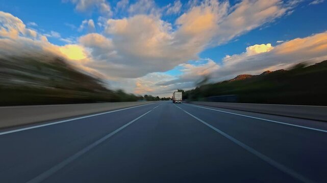 Timelapse of road drive along the highway. Front view to the road and surrounding landscapes. Trees stretch on both sides of road. Fast car hyperlapse. Road trip travel concept sort of dashcam POV