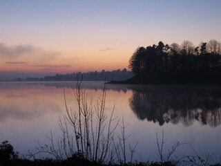 Sunset over the mirror-smooth waters of Mugdock Reservoir, Milngavie on a cold winter's day