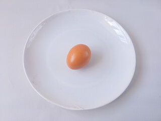 chicken egg on a round white plate isolate on white. vegan concept. protein rich food. diet menu