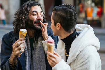 Gay couple sharing ice cream cones and affection on city street