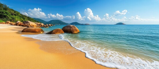 Obraz premium Beach scenery with turquoise water golden sand and granite rocks under a clear blue sky showcasing peaceful coastal beauty and relaxation