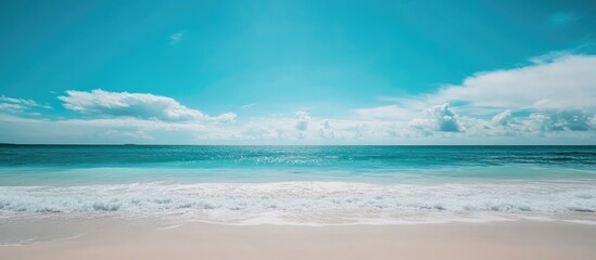 Obraz premium Tranquil beach scene with azure sea, clear skies, and soft sand perfect for vacation inspiration and relaxation imagery.