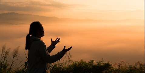 Christian woman raised her hand in worship and prayer to God, seeking peace through Jesus Christ during a serene sunrise morning. worship, christian, jesus christ, hand, god, peace, pray, sunrise.