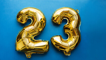 Banner with number 23 golden balloon on blue backdrop. Birthday anniversary celebration.