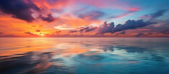 Vibrant sunset over the calm ocean with colorful reflections creating a serene coastal landscape at dusk
