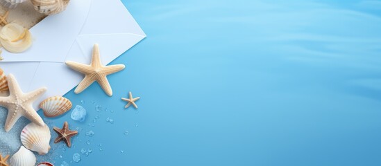 Seashells and starfish arranged beside an envelope on a serene blue background for coastal themed invitations or announcements