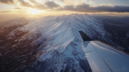 Airplane wing view over snowy mountains during flight descent