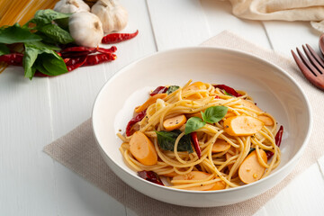 Spaghetti with Sausage and Dried Chili.Spicy stir fried Spaghetti with smoky bite ,garlic and crispy chilli in white plate.