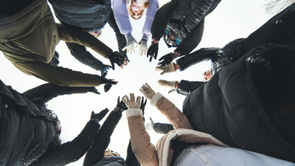 Schoolgirls wearing winter clothes and gloves, forming a circle with their hands together for a snowy photo shoot