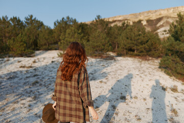 red haired woman walking on sandy beach with long shadow in golden hour light