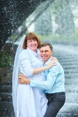 Fototapeta premium An adult bride and groom at the fountain. Husband and wife's wedding anniversary photo shoot. We've been together for 30 years.