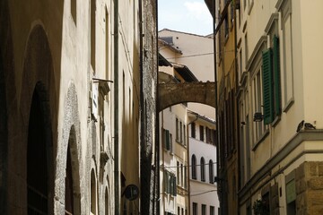 Sunlit alleyway in Florence with stone bridge