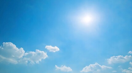 Fototapeta premium Vivid blue sky with bright sun and fluffy white clouds.