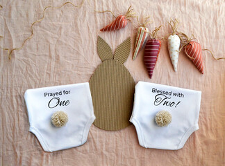 Easter baby twins Birth announcement template. Pregnancy announcement. Little Easter Bunny. mockup Blank white onesie and  booties.  flat lay. Spring baby birth announcement.