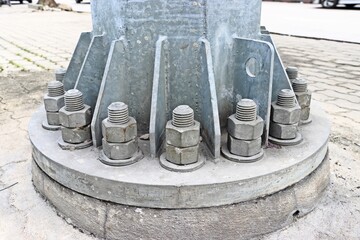 Metal pillar bolted to concrete foundation of street public spotlight pole