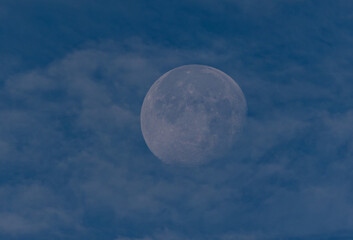 waning moon hiding in the morning between clouds