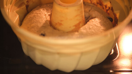 Bundt cake batter rising in the oven during baking. Close-up view of dessert preparation process. Homemade baking and cooking concept.