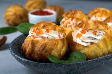 Profiteroles with red caviar and cream cheese with dill. Festive appetizer, buffet dish