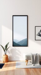 Minimalist living room interior with a mountain landscape framed print on a white wall, a white ottoman with a throw blanket on a white rug, and a potted plant on a hardwood floor.
