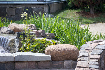A stone garden with flowers and a small waterfall between the stones