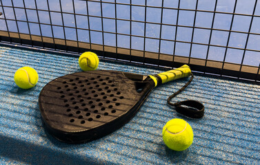  padel racket and yellow balls placed on court near net 