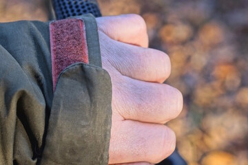 one red plastic rectangular velcro closure on green clothing fabric with fingers on the autumn street