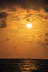 The sun is setting over the ocean, casting a warm glow on the water