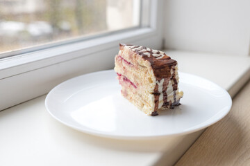 A piece of chocolate pie Milchmadchen with cheese cream sauce with banana and cherry on the windowsill. Traditional German cake. Ready to eat.