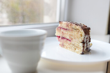 A piece of chocolate pie Milchmadchen with cheese cream sauce with banana and cherry on the windowsill. Traditional German cake. Ready to eat.
