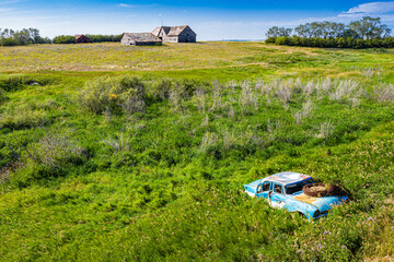 A blue car is sitting in a field of grass