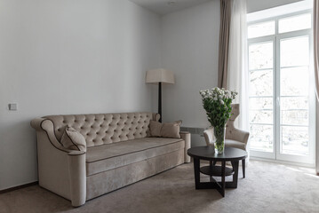 White Rose Flower On the Table with Couch and Window in Background. Room Interior.