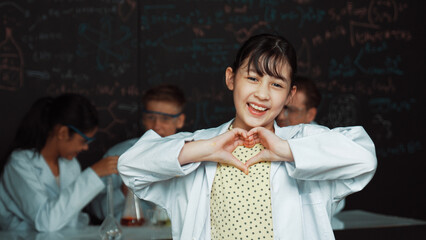 Asian scientist show miniheart to camera while diverse group doing experiment. Young schoolgirl...