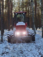 Abandoned combine harvest  in forest with lighted main lights between trees.