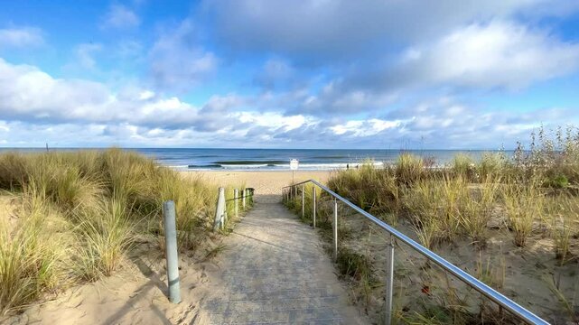 path to the beach through the dunes, sunny day with blue sky and white clouds 